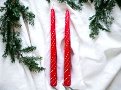 two red candles sitting on top of a white sheet