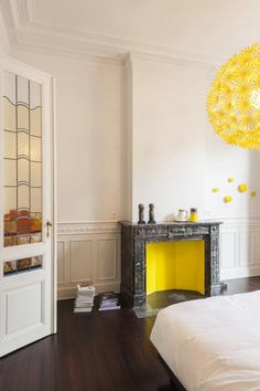 a bedroom with white walls and wood floors has a yellow fire place in the corner