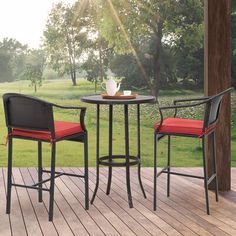 two chairs and a table on a wooden deck with grass in the backround