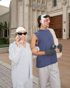 a man and woman standing in front of a church talking on their cell phones while wearing blindfolds