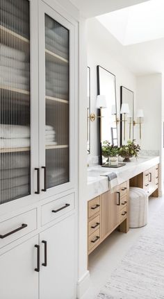 a white bathroom with glass doors and drawers on both sides is shown in this image