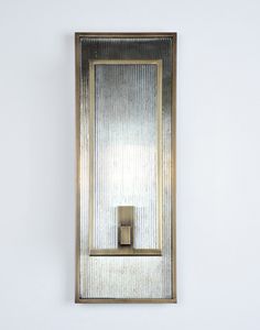 a wall mounted light with a metal frame and square mirror on it's side