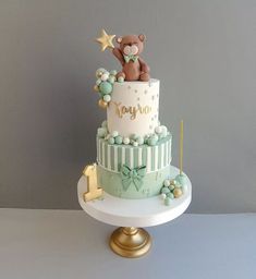 a baby shower cake with a teddy bear on top and stars around the edges, sitting on a pedestal