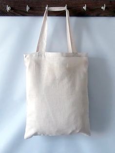 a white tote bag hanging on a wooden coat rack in front of a blue wall