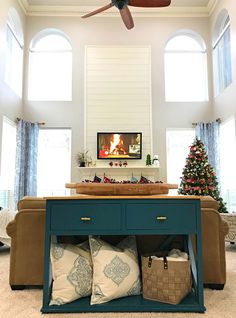 a living room filled with furniture and a christmas tree in the corner under a ceiling fan