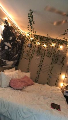 an unmade bed in a room with lights on the wall and plants hanging from the ceiling