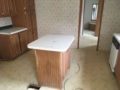 an empty kitchen with wood cabinets and white counter tops in the process of remodeling