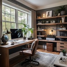 a desk with a computer on top of it in front of a window and bookshelf