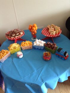 a blue table topped with lots of different foods and desserts on top of it