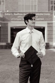 a man standing in front of a building with his hands on his hips wearing a tie