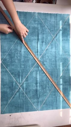 someone is measuring the length of a blue rug with a ruler on top of it