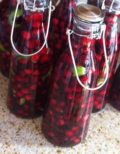 several jars filled with red and green cherries sitting on a counter next to each other