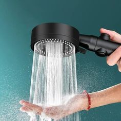 a hand holding a shower head with water coming out of it's side and spraying the