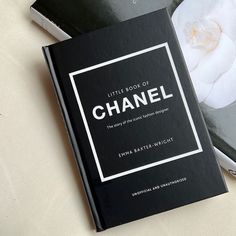 the little book of chanel is sitting on top of a table next to a white flower