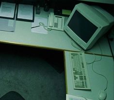 an office desk with a computer, phone and other electronic equipment on top of it