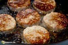 four hamburger patties cooking in a skillet with oil on the bottom and brown sugar on top