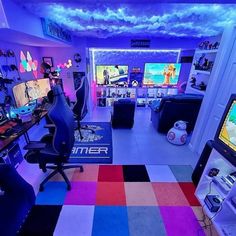 a room filled with lots of computer monitors and gaming equipment on top of colorful carpeted floors