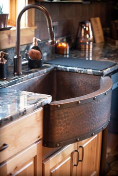 a kitchen sink sitting under a faucet next to a window