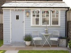 a small blue shed with two chairs and a table