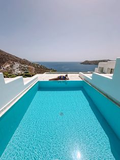 an empty swimming pool in the middle of a house with blue water and white walls