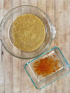 two glass bowls filled with spices on top of a wooden table next to another bowl