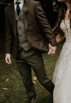 a bride and groom holding hands walking through the grass