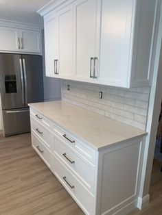 a kitchen with white cabinets and stainless steel refrigerator freezer next to it's counter top