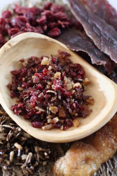 a wooden spoon filled with dried cranberries on top of a table next to other items