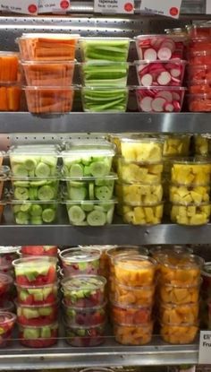 many different types of fruits and vegetables are on display in a grocery store, including apples, cucumbers, celery, carrots