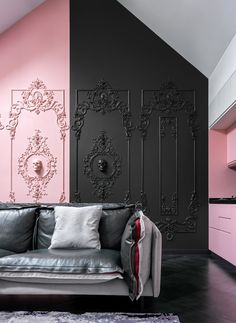 a black and pink living room with an ornate design on the wall, couches and rugs