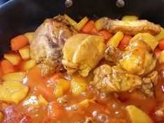 chicken, carrots and potatoes are in a pan on the stove top ready to be cooked