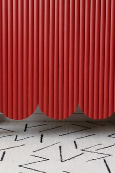 a red radiator sitting on top of a white floor next to a rug