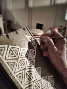 a person is drawing designs on a piece of wood