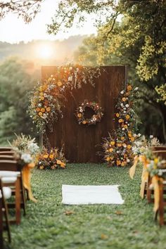 an outdoor ceremony set up with flowers and greenery on the grass, surrounded by wooden chairs