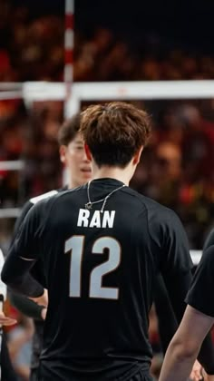 two young men standing next to each other in front of a basketball court with fans