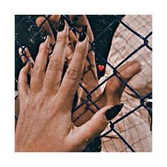 two hands touching each other behind a chain link fence with red hearts on their fingers