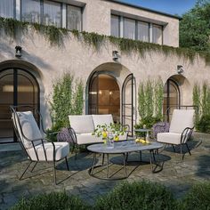 an outdoor seating area with chairs and tables in front of a stucco building that has ivy growing on it