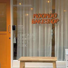 a wooden bench sitting in front of a window with the words moonoo bakeshop on it