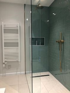 a bathroom with a glass shower door and tiled walls, along with a towel rack on the wall