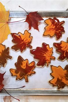 maple leaf cookies on a baking sheet with autumn leaves