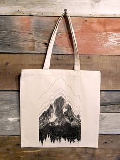 a tote bag hanging on a wooden wall with mountains and trees in the background