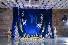 the stage is decorated with white flowers and blue draping for an elegant wedding