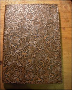 an intricately carved leather book sitting on top of a wooden table