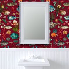 a bathroom sink sitting under a mirror in front of a wall mounted mirror with fish on it