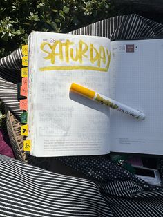 an open notebook with the word saturday written on it and a yellow marker sticking out of it