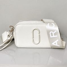 Authentic Marc Jacob’s Snapshot Bag In Cream + Champagne. Champagne Strap With Gold Detailing. Strap Included And Bag! Saffiano Leather Dual Top Zip Closure Removable And Adjustable Webbing Strap Interior Slip Pocket, Exterior Slip Pocket Faille Lining 7in L X 2in D X 4in H 18cm L X 6cm D X 11cm H Strap 8-57in L X 2in D (21-144 Cm L X 5cm D) Strap Drop 27in (68cm) Designer Bags With Logo Strap, Designer Bags With Logo Strap For Everyday, Designer Everyday Bag With Logo Strap, Classic Bags With Logo Strap For Daily Use, White Bag With Logo Strap For Everyday Use, Luxury Beige Shoulder Bag With Logo Strap, White Bags With Logo Strap For Everyday Use, Elegant White Bags With Logo Strap, Luxury White Shoulder Bag With Logo Strap