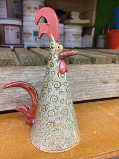 a ceramic rooster figurine sitting on top of a wooden table