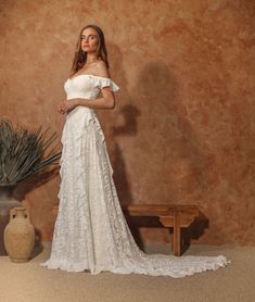 a woman standing in front of a wall wearing a white dress