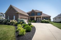 a large brick house with landscaping in the front yard and driveway leading up to it