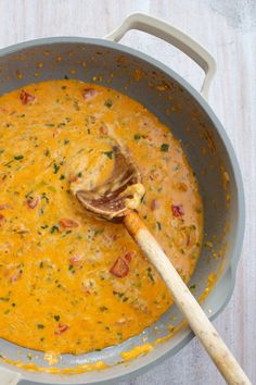 a wooden spoon in a large pot filled with cheese and other food items on a table